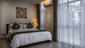 Una habitación de hotel con una cama grande, aire acondicionado de pared y cortinas traslúcidas.