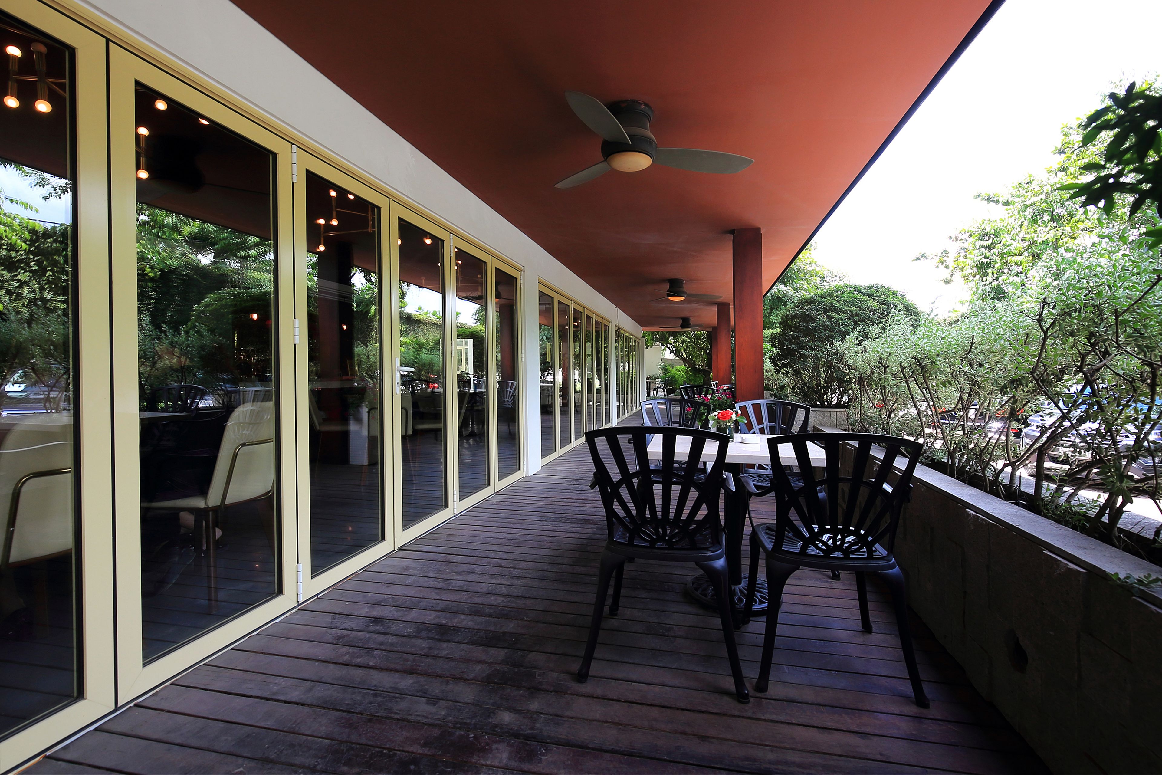 An outdoor dining area with a wooden deck, black chairs, and a table.
