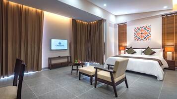 A hotel room with a bed, a TV, a desk, and a chair.