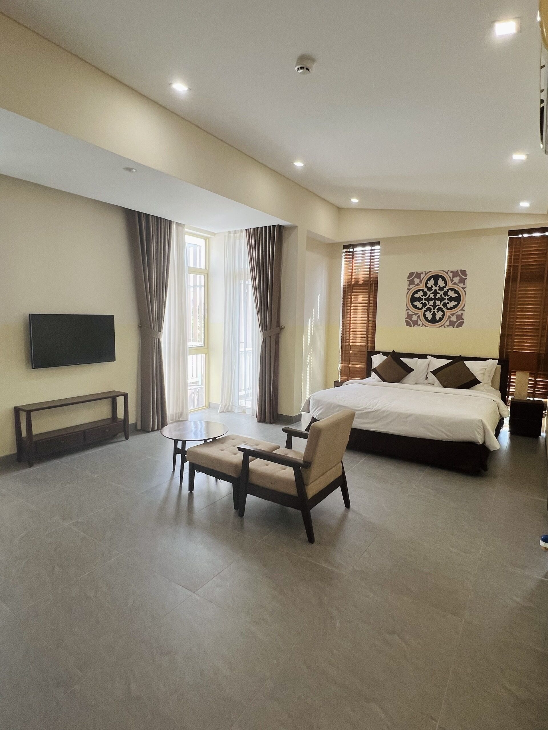 A hotel room with a bed, a TV, a small table, and a chair.
