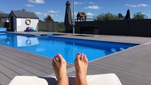 A pool area with a view of a building in the background. - Cottages on St Andrews (Havelock North)