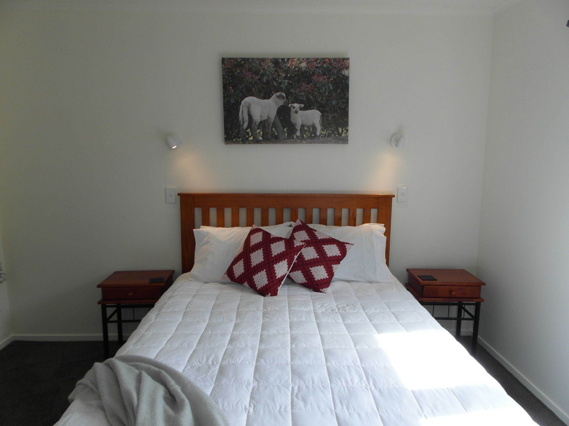 A bedroom with a large bed, two bedside tables, and a painting on the wall.