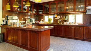 A spacious kitchen with wooden cabinets, a large island, and pendant lighting. - Warmhouse (Taitung)