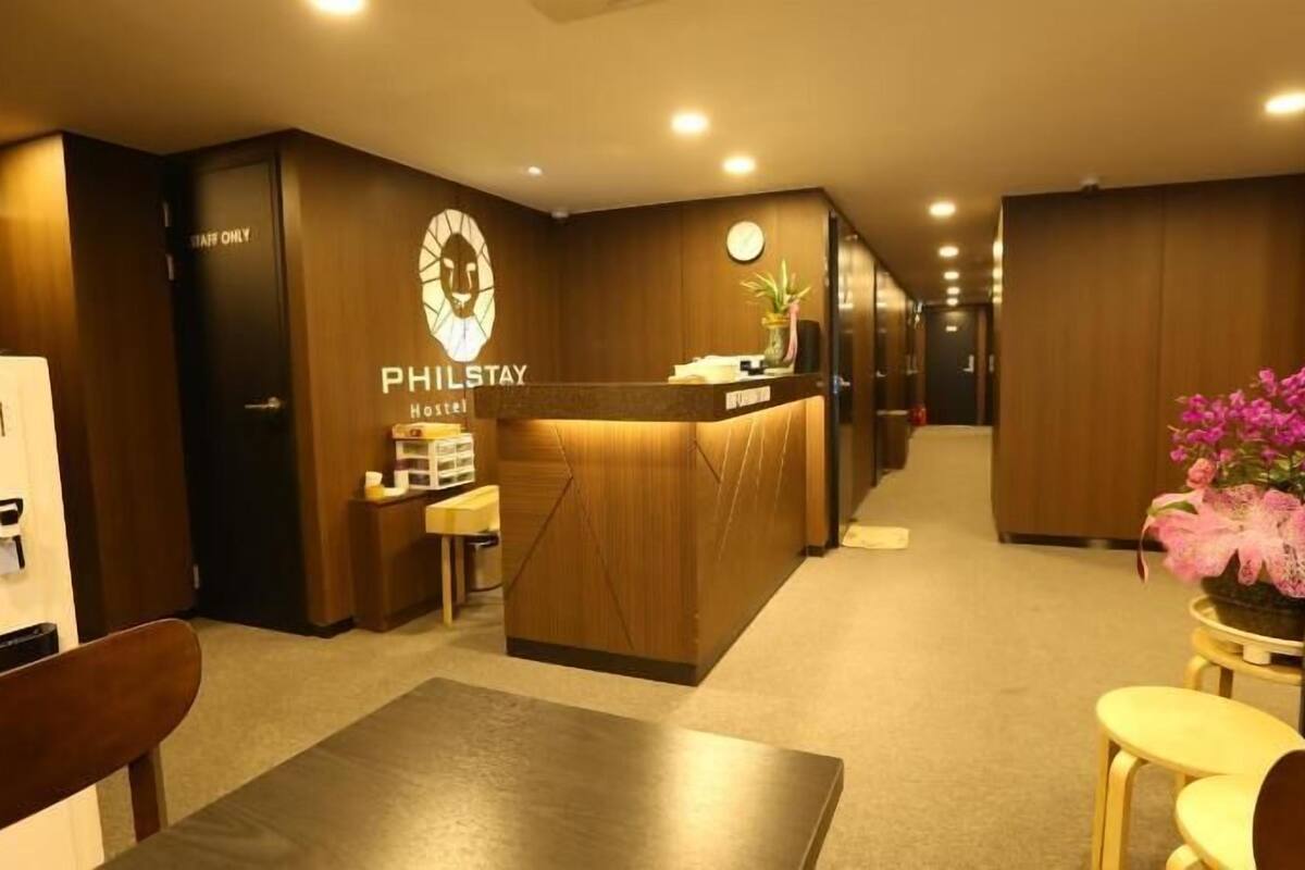 A hotel reception area with a reception desk, a clock, and a small plant.