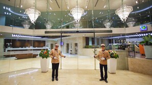 Een moderne hotellobby met kroonluchters, een receptiebalie en een zithoek.