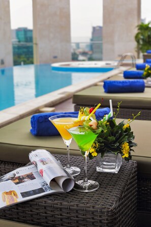 Un cadre agréable au bord de la piscine, avec un fauteuil de relaxation, une boisson agrémentée d’une garniture et un magazine.