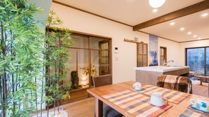 A modern kitchen with a wooden table and chairs, a sink, and a window with a view. - Your Pavilion near Kinkakuji (Kyoto)