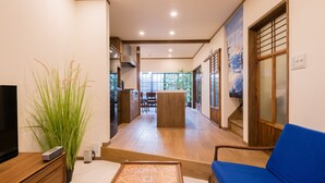 A modern living room with a TV, a blue sofa, a wooden coffee table, and a large plant. - Your Pavilion near Kinkakuji (Kyoto)