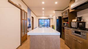 A modern kitchen with a central island, wooden cabinets, and built-in appliances. - Your Pavilion near Kinkakuji (Kyoto)