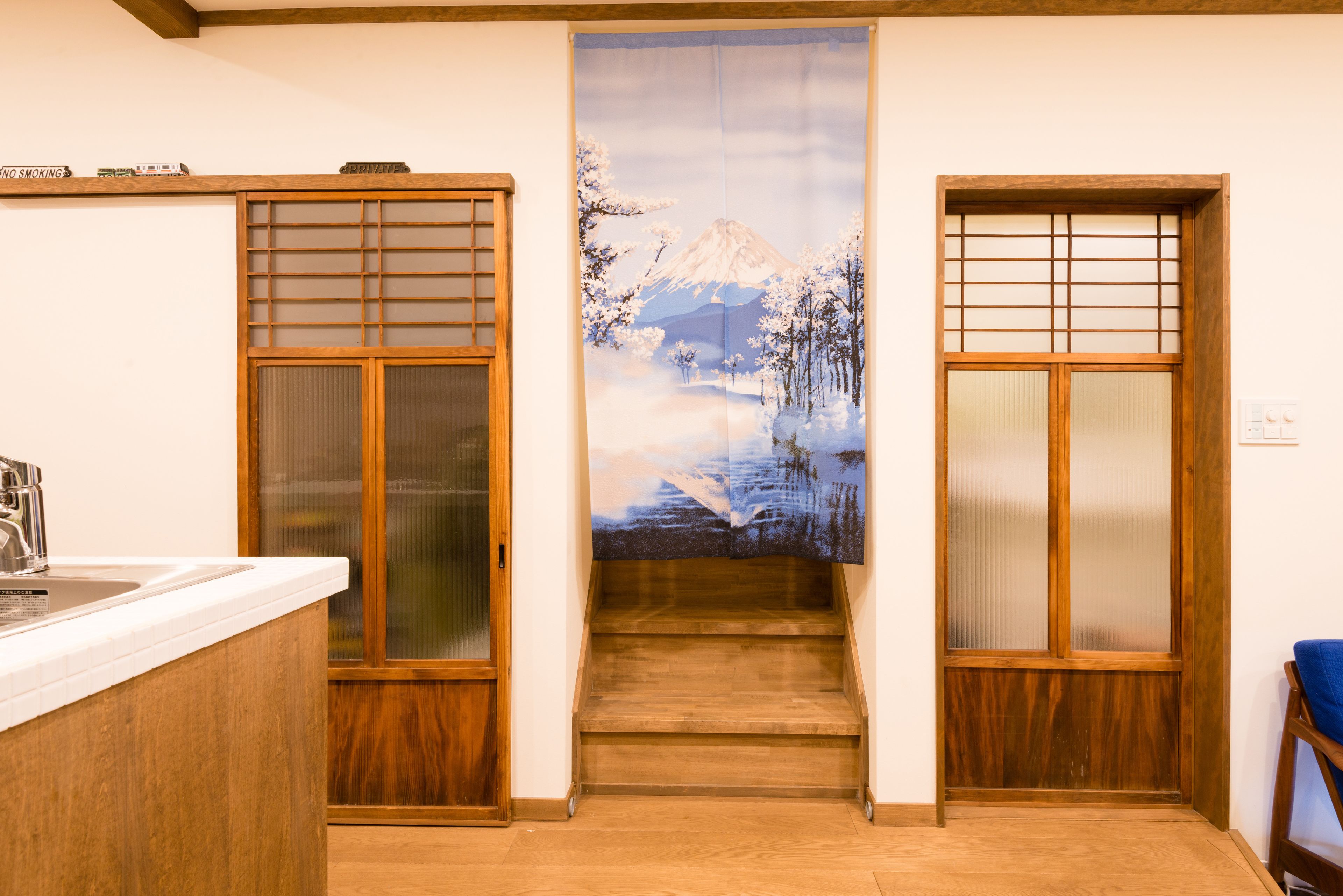 Une chambre d’hôtel avec une porte coulissante donnant sur un escalier, un lavabo avec un robinet et un plancher en bois.