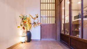 A wooden floor leading to a traditional Japanese-style room with a sliding door and a display of books and items on shelves. - Your Pavilion near Kinkakuji (Kyoto)