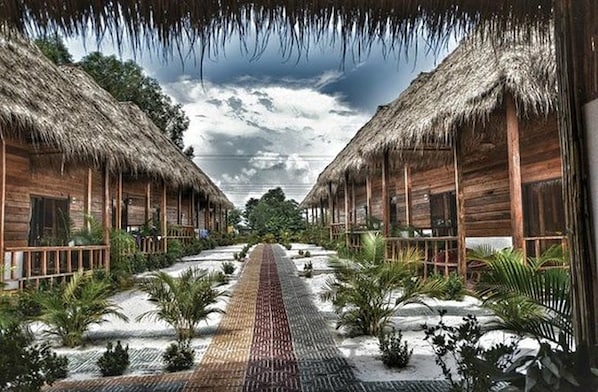 A row of wooden cabins with thatched roofs, arranged in a symmetrical pattern with a central pathway.
