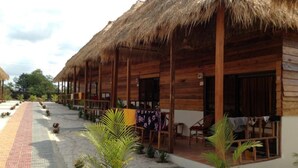 Une rangée de cabanes en bois aux toits de chaume, disposées le long d’une allée pavée.