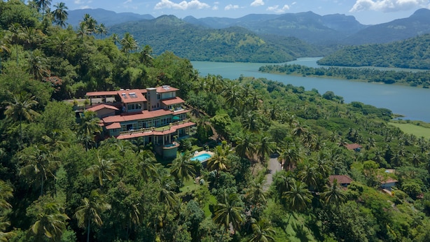 A large, multi-story building surrounded by lush greenery and a lake. - The Albatross, Kandy (Maberiyatenna)