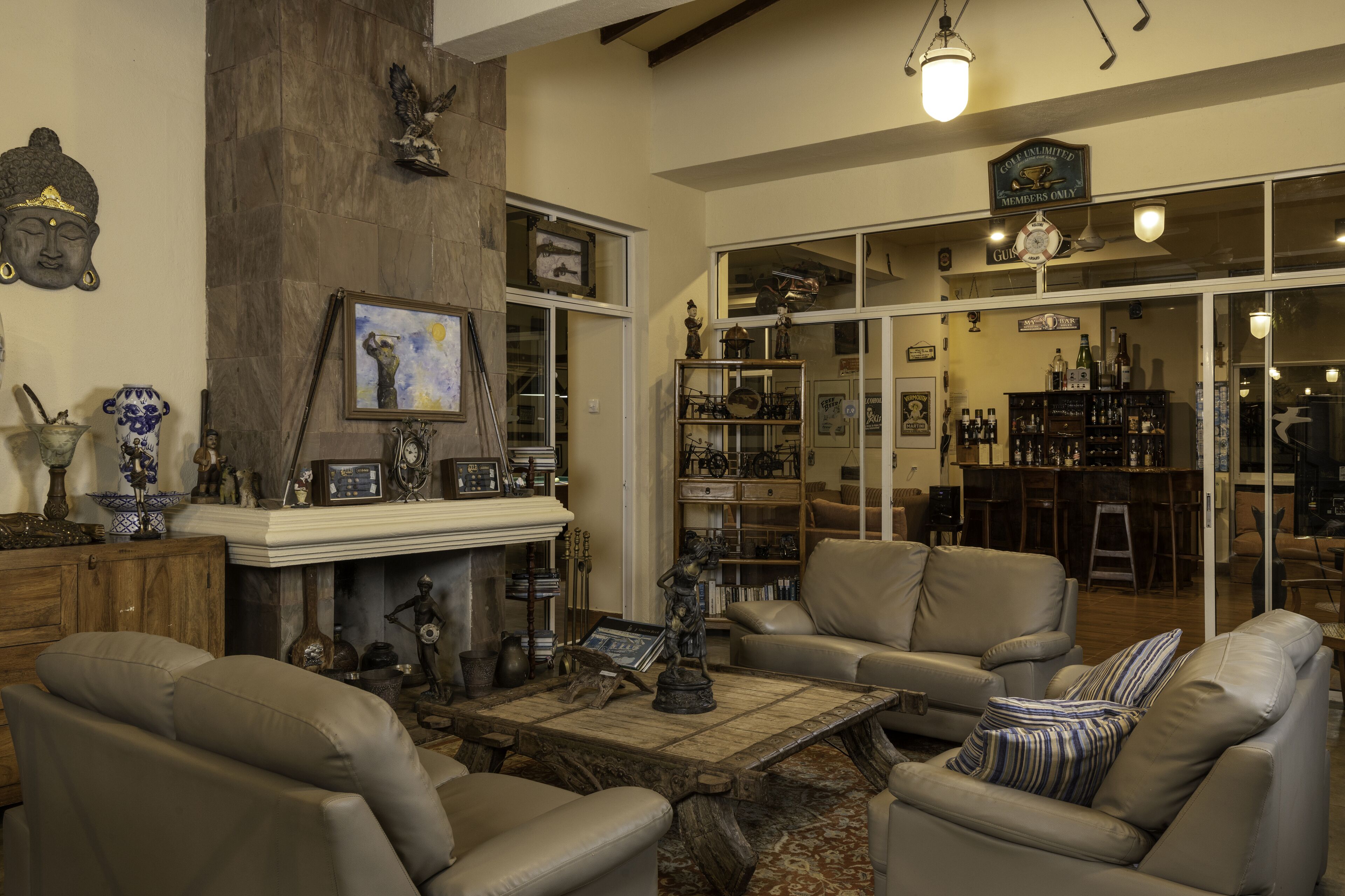 A cozy living room with leather sofas, a fireplace, and a bar area visible through glass doors.