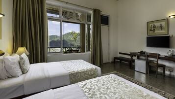 A hotel room with two beds, a desk, a chair, a TV, and a window with curtains.