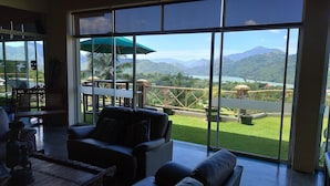 A spacious room with large windows offering a view of a lush garden and mountains. - The Albatross, Kandy (Maberiyatenna)
