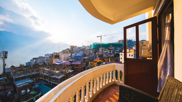 A balcony with a view of a cityscape, including buildings and a construction crane.