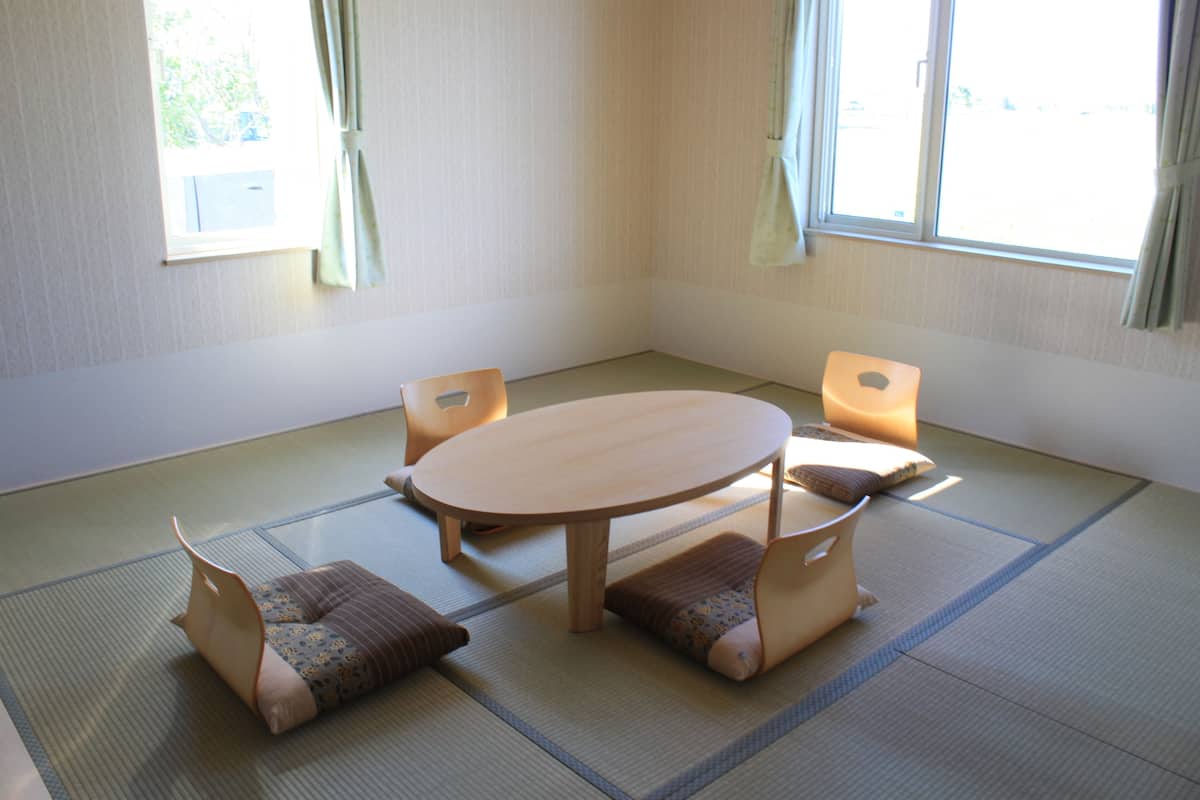 Een kamer met tatami matten, een ronde tafel en vier stoelen.