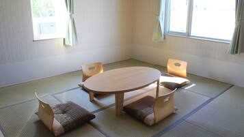 A tatami mat room with a round table and four chairs.