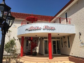 A building with a sign reading "Blane Fleur" and a red spiral staircase leading to a balcony. - Petit Hotel Blanc Fleur (Nakafurano)