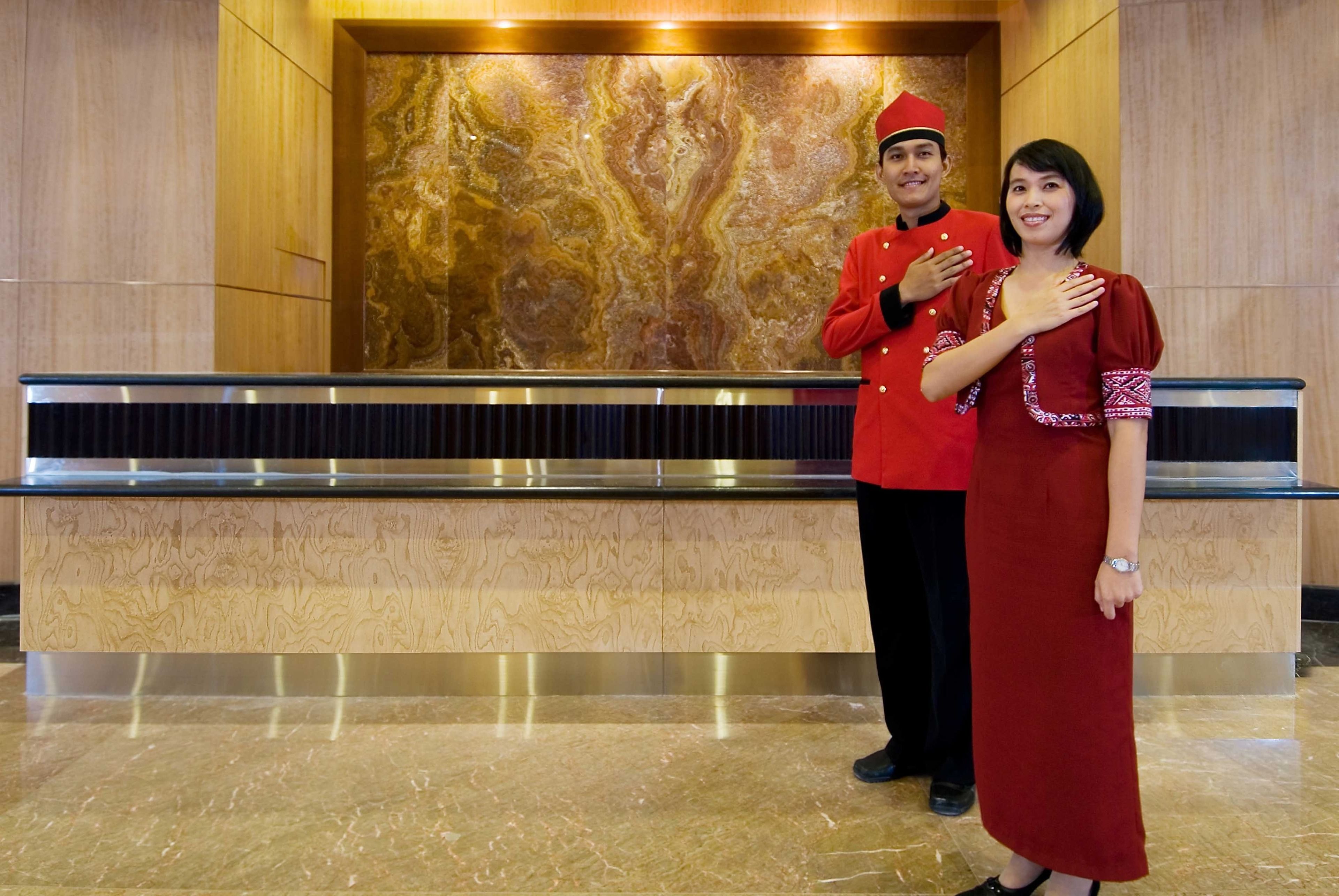 A reception area with a marble wall and a reception desk.