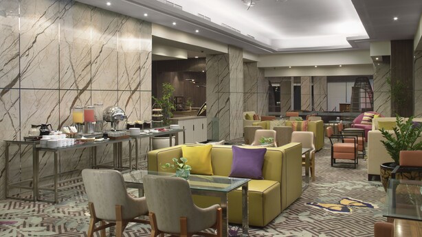 A modern hotel lobby with marble walls, a glass coffee table, and comfortable seating areas. - Aston Manado Hotel (Manado)