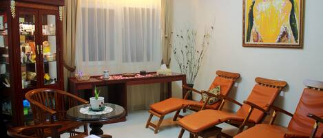 A living room with a wooden cabinet, a dining table, and four orange chairs.