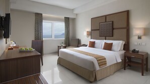 A hotel room with a large bed, bedside tables, a desk, and a television. - Aston Manado Hotel (Manado)