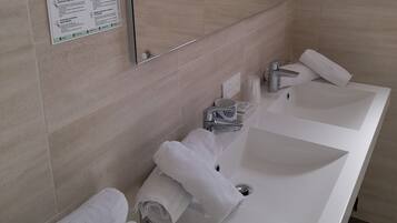 A modern bathroom with two sinks, a large mirror, and a towel rack.