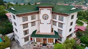 A multi-story building with a central courtyard, surrounded by lush greenery and mountains in the background. - Bhutan Suites (Thimphu)