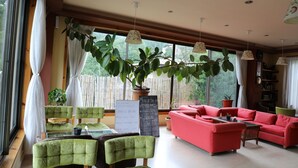 A spacious living room with a red sofa, green chairs, a coffee table, and a large potted plant. - Bhutan Suites (Thimphu)