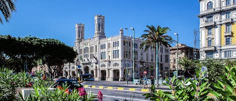A historic building with ornate architecture, a prominent clock tower, and a street with cars and pedestrians.