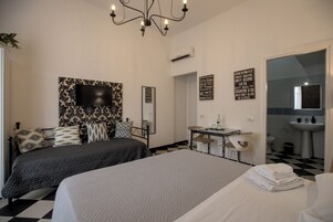 Una habitación de hotel con dos camas, un escritorio, una silla, un televisor y un baño.
