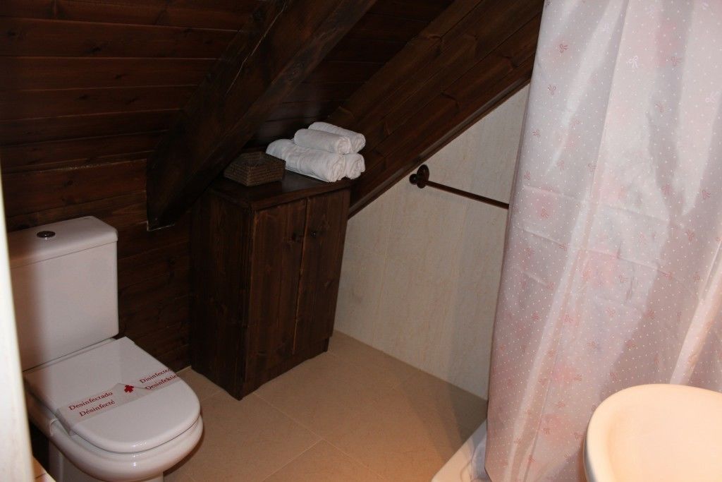 Ein kleines Badezimmer mit Holzboden, einer weißen Toilette und einem Handtuchhalter.