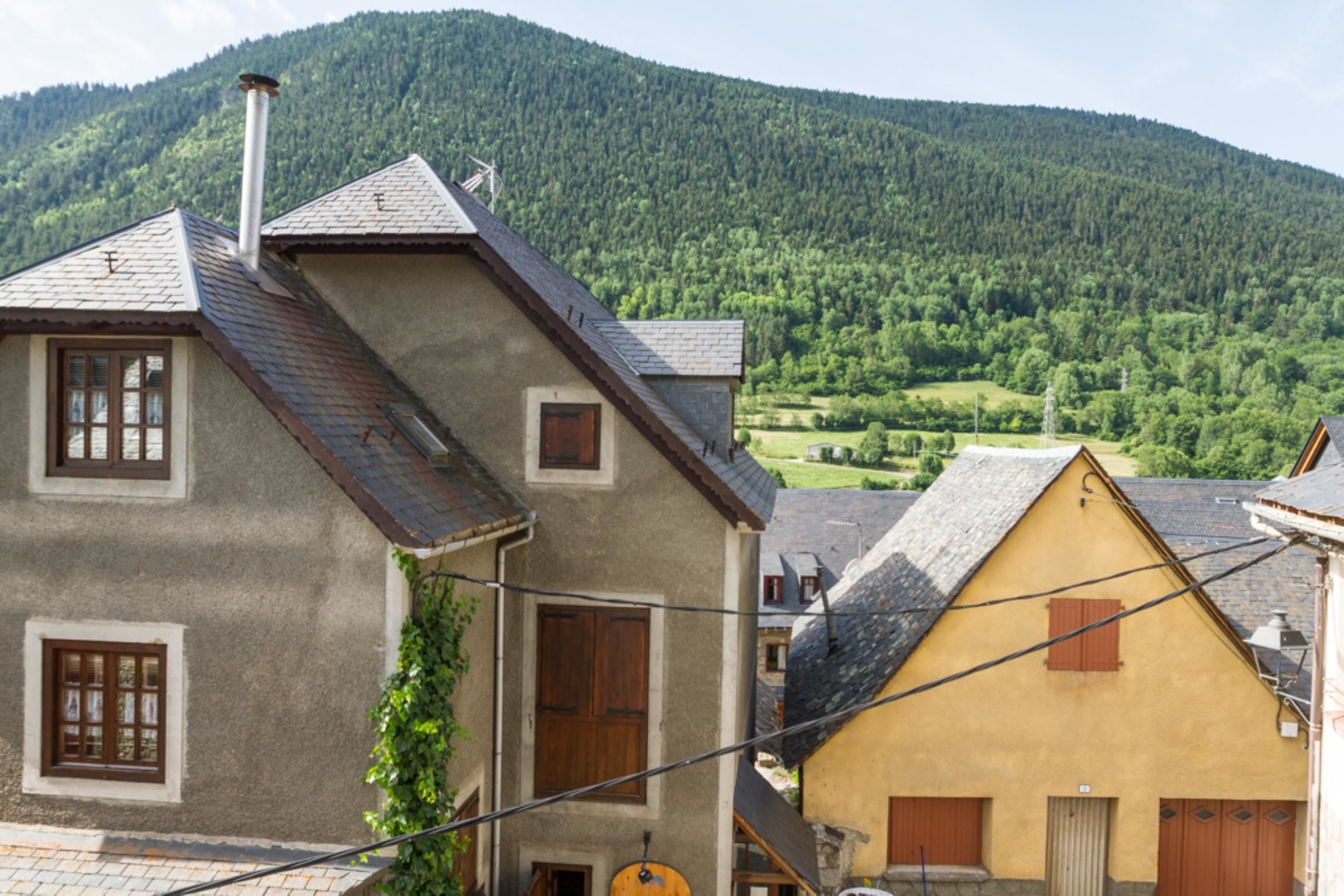 A traditional European building with a sloped roof, a chimney, and a window with shutters.