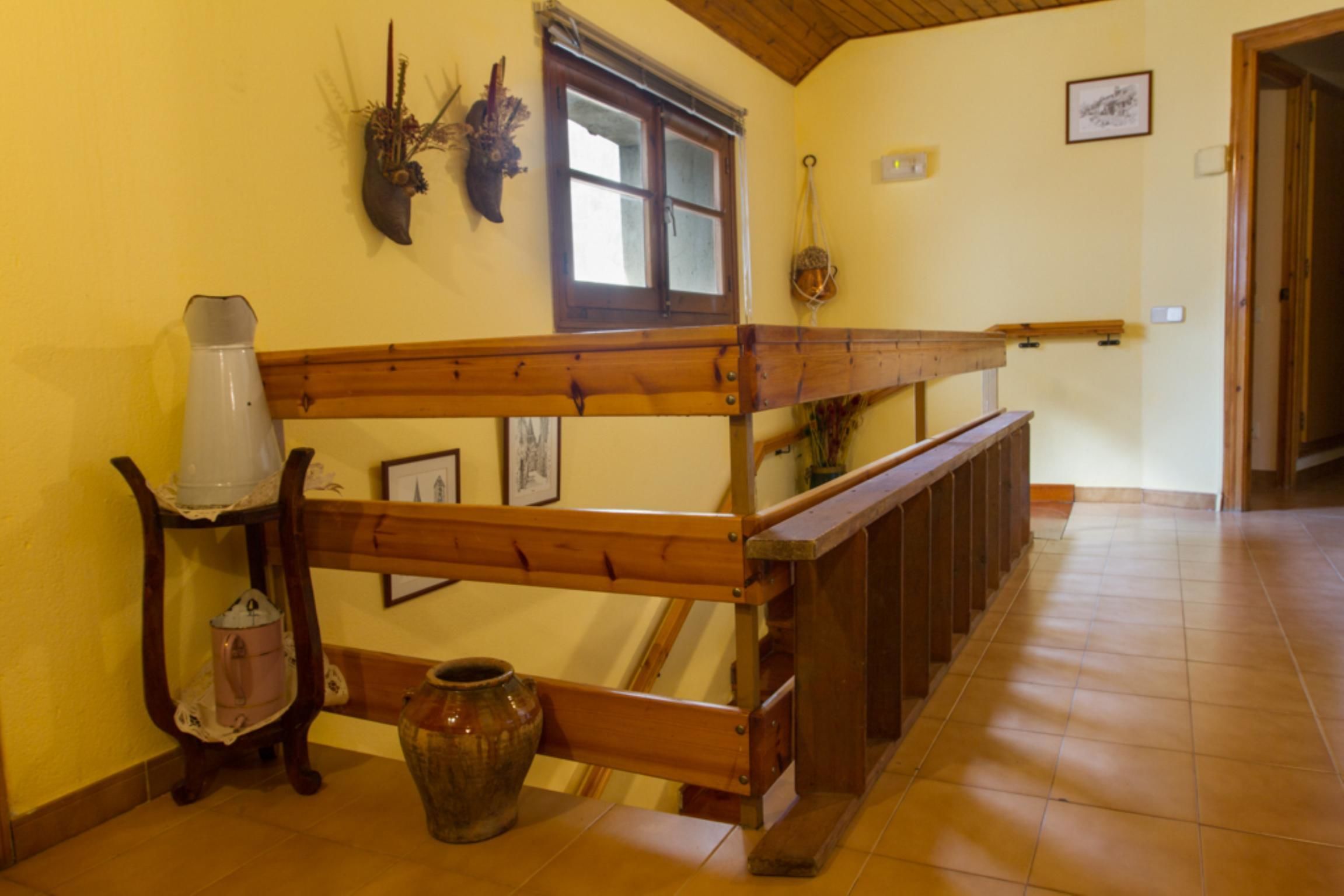 A wooden staircase with a handrail, a vase, and a wall-mounted decorative item.