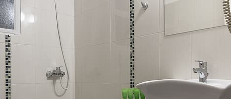 Un baño con ducha, lavamanos y espejo.