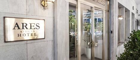 Das Ares Athens Hotel von außen mit einem Schild, Eingangstüren und einem Blumentopf.