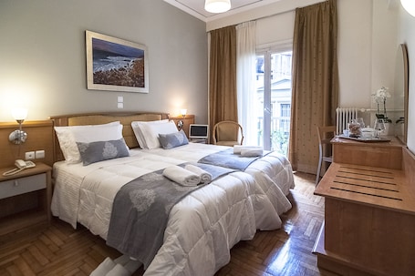 A hotel room with a large bed, bedside tables, a desk, and a view of the outdoors.