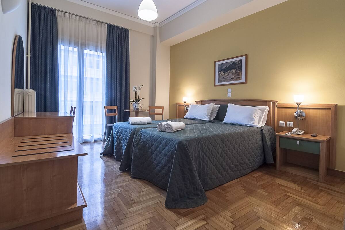 A hotel room with a bed, bedside tables, a desk, and a chair.