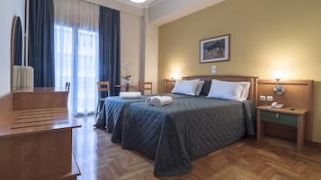 A hotel room with a bed, bedside tables, a desk, and a chair.