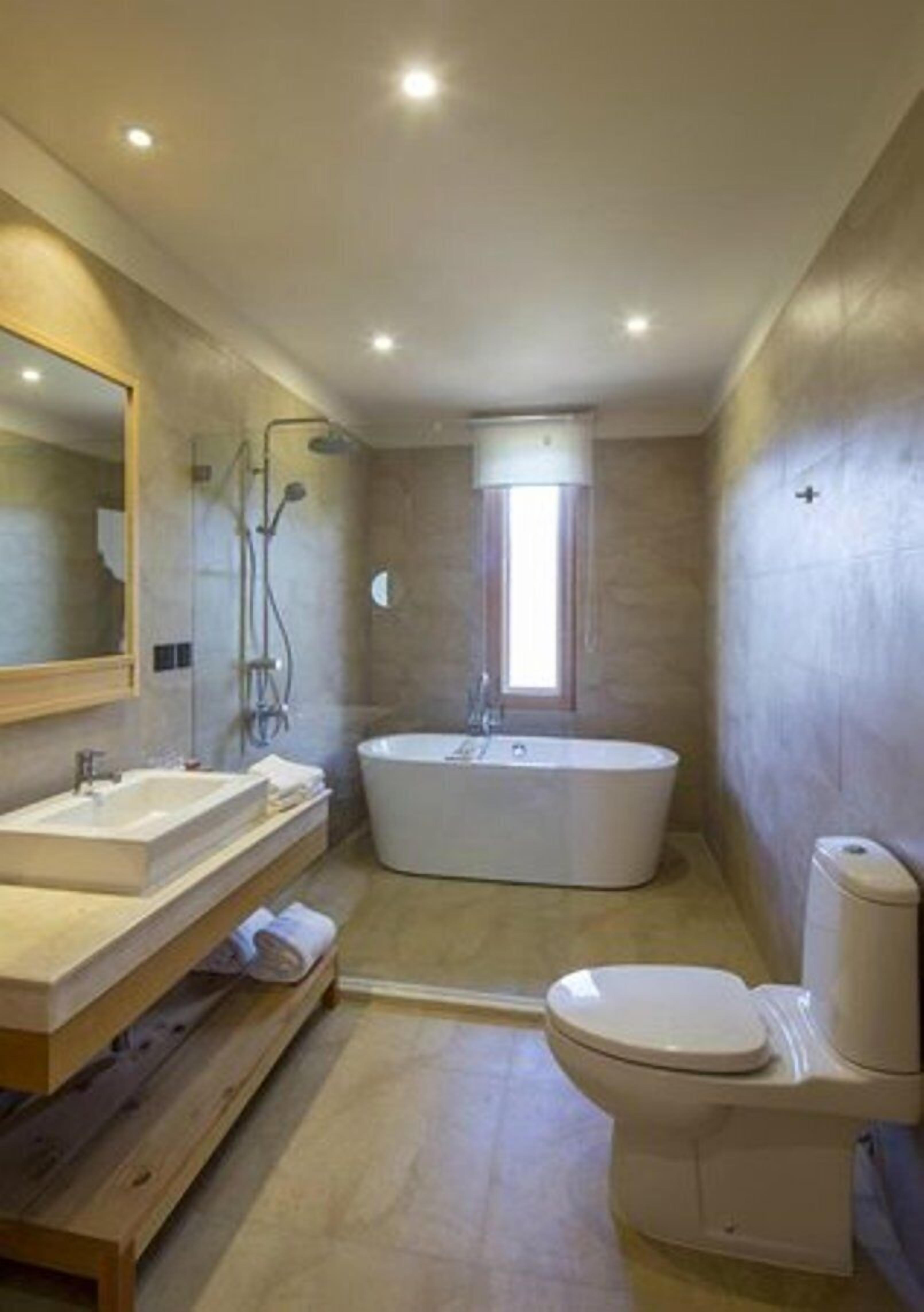 A modern bathroom with a freestanding bathtub, a toilet, and a vanity with a mirror.