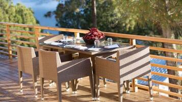 Un comedor con mobiliario de mimbre y una mesa dispuesta para cuatro, con vistas panorámicas.