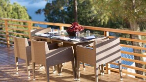 Un comedor con mobiliario de mimbre y una mesa dispuesta para cuatro, con vistas panorámicas.