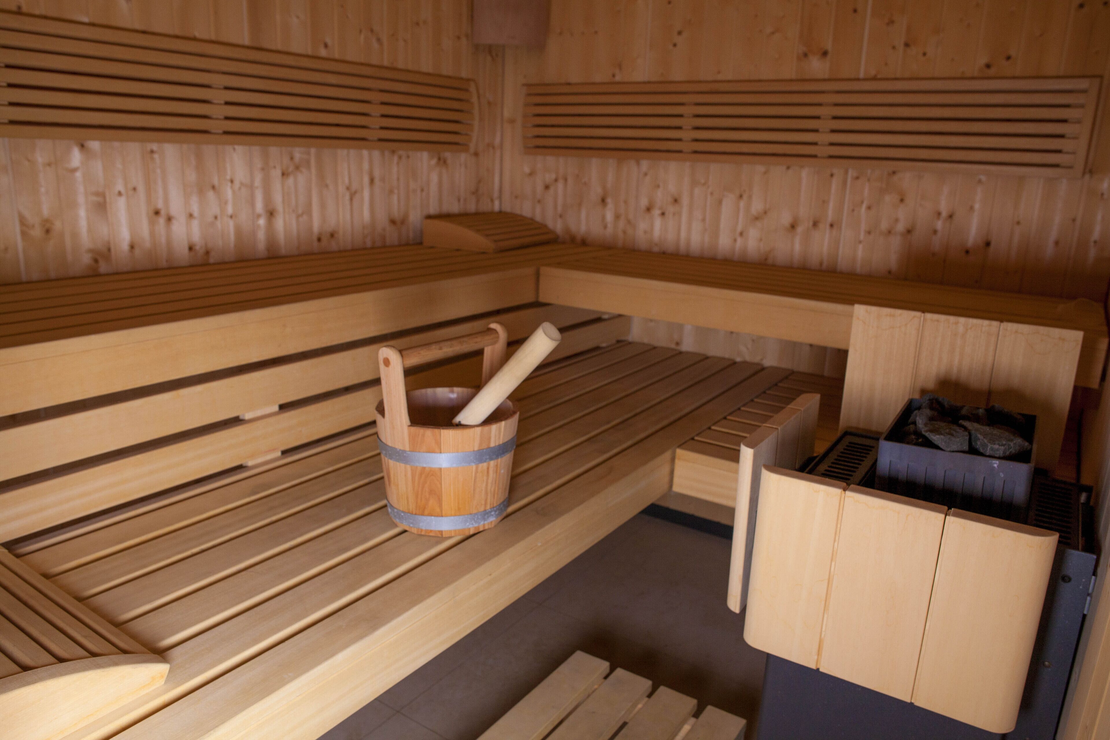 Una sauna con bancos de madera y un balde de madera.