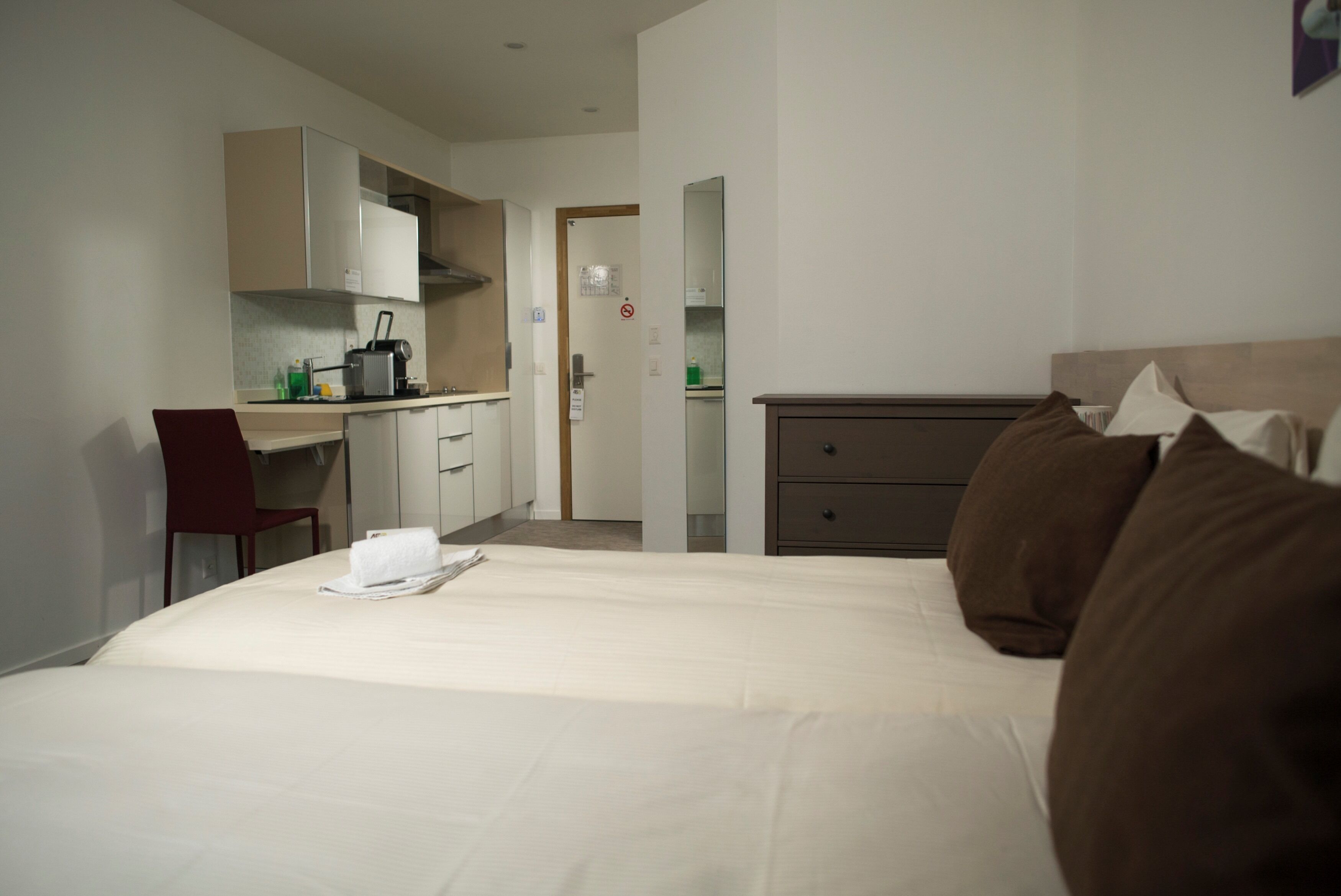 Une chambre d’hôtel avec un lit, un bureau et une kitchenette.