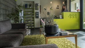 Un área de recepción moderna con un mostrador verde, un sofá, una mesa de centro y una estantería.