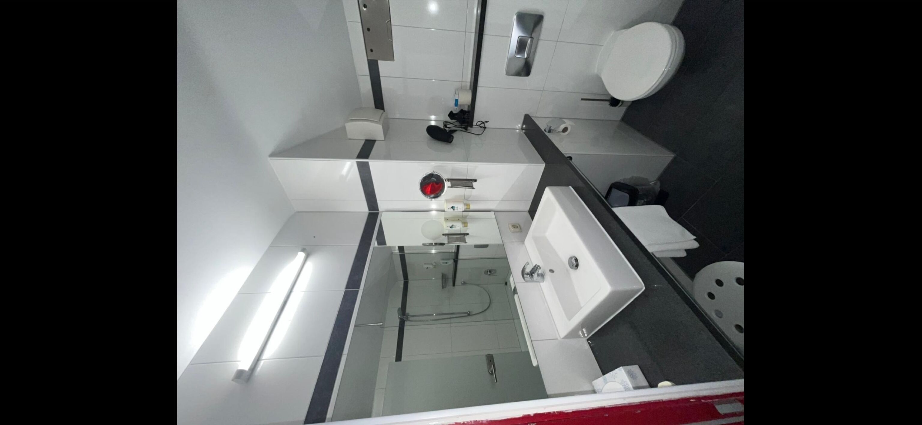 A modern bathroom with a white sink, mirror, and toilet.