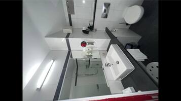 A modern bathroom with a white sink, mirror, and toilet.